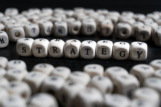 Word strategy on wooden cubes on a black wooden table
