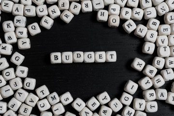 Word BUDGET on wooden cubes on a black wooden table with copy space