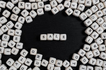 Word SALE on wooden cubes on a black wooden table with copy space