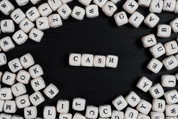 Word CASH on wooden cubes on a black wooden table with copy space