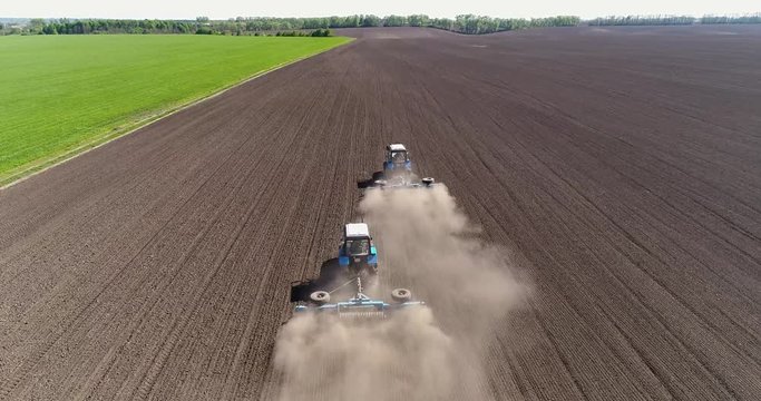 Aerial view of agricultural tractors cultivating field.