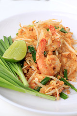 Pad Thai, stir-fried rice noodles with shrimp in white plate with slide lemon and green vegetable. The one of Thailand's national main dish. the popular food in Thailand. Thai Fried Noodles