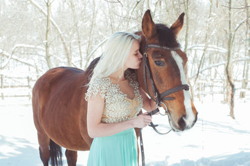 Obraz premium Blonde woman kissing her horse, winter time