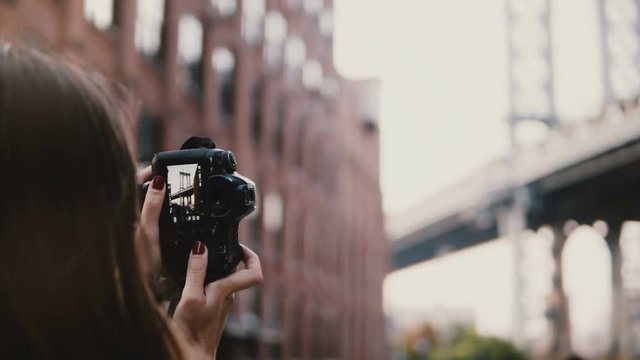 Back view unrecognizable woman with camera takes photos of Brooklyn Bridge at Dumbo District in New York City 4K.