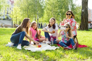 Rest in the park. Mothers with children sit on the grass, women drink coffee, children eat apples