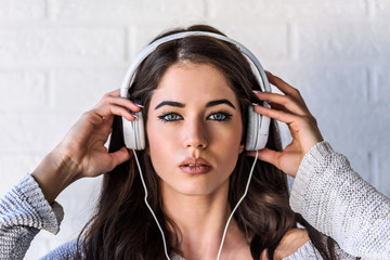 Portrait of beautiful young urban woman with headphones indoors listening music