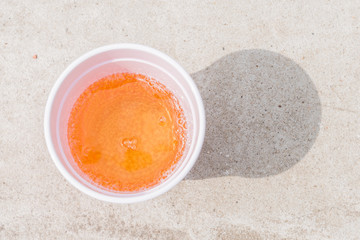 Carbonated apple juice on a stone surface in a plastic glass - top view
