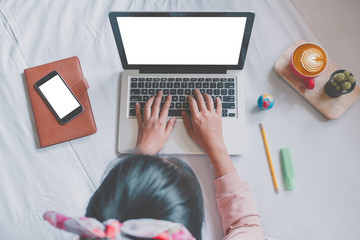 Happy casual beautiful woman working on a laptop and smartphone with blank screen