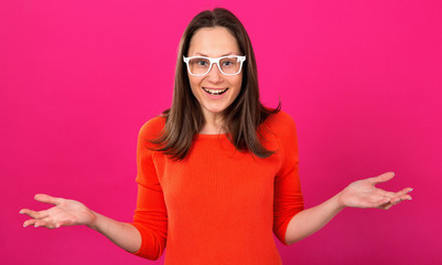Wow! Surprised, delighted woman brunette with glasses on a pink background.