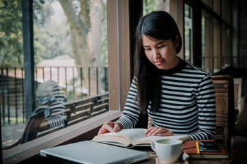 Hipster woman teenager sitting enjoy reading book at cafe.