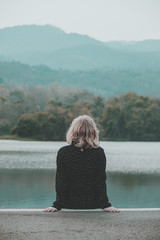 Fototapeta premium Teenager girl sitting alone in the park on moutain background.