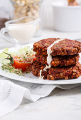 Vegan burgers from lentils, oats and vegetables. Veggie cutlets served with green salad and tomatoes.