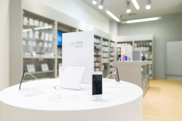 Smartphones on a showcase in a modern electronics store. Smartphone on the background of a light...