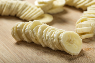 Fresh raw banana slices on wood cutting board - close-up view