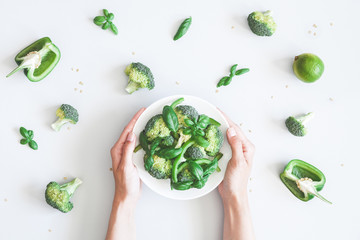 Woman holding green vegetable salad. Vegan, vegetarian concept. Flat lay, top view