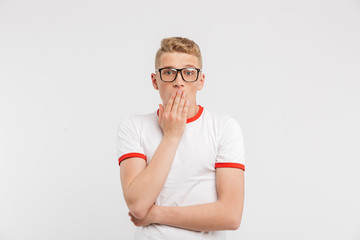 Photo of scared guy in eyeglasses looking at you and covering mouth in fear or shock, isolated over white background