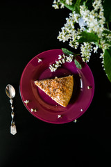 Piece of cake served with bouquet of flowers on a black background