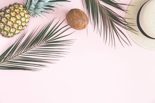 Summer composition. Tropical palm leaves, hat, pineapple, coconut on pastel pink background. Summer concept. Flat lay, top view, copy space