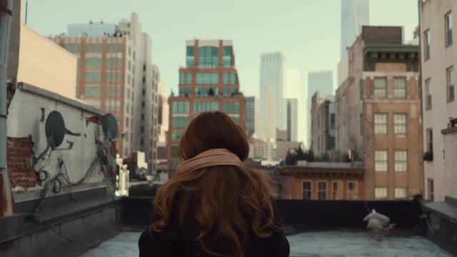 Back View Shot of Beautiful Woman Walking on a Roof, Turning Around and Smiling Wind Shuffles Her Long Red Hair. Shot on RED Epic 4K UHD Camera.