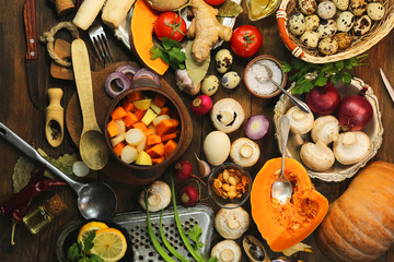 cut mushrooms, pumpkin and potatoes in a clay pot. cooking healthy food. spices and ingredients. wooden background.