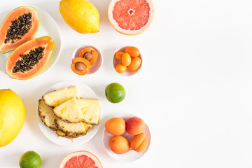 Summer fruits. Pineapple, papaya, orange, apricot, lime, lemon on white background. Flat lay, top view, copy space