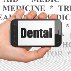 Healthcare concept: Hand Holding Smartphone with  black text Dental on display,  Tag Cloud background, 3D rendering