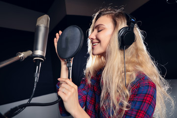 Play on! Gorgeous good-looking female vocal artist singing in the modern recording studio in order...