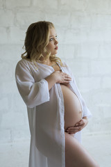 Young pregnant girl in dressing gown profile view