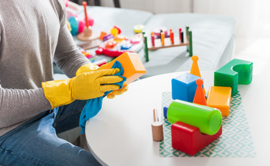Young handsome father cleaning toys and table after playing with his child at home