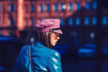 portrait of a stylish woman posing in a leather jacket and hat