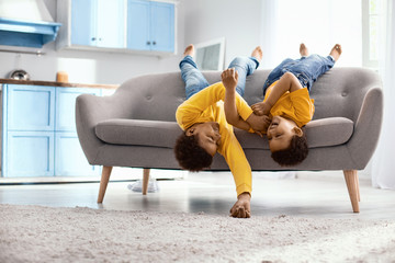 Playing around. Cheerful little brothers lying on the sofa upside down and tickling each other...
