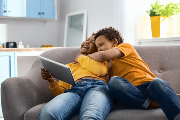Immense affection. Kind little boy sitting on the sofa next to elder brother and hugging him while...