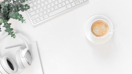 Modern white office desk table with laptop computer, notepad, plant, headphones and cup of coffee....