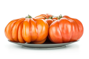 Three beef tomatoes on a grey ceramic plate isolated on white background big ripe red ribbing.