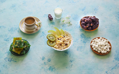 Breakfast with muesli on turquoise background. Muesli with Turkish sweets, kiwi, dates and milk.
