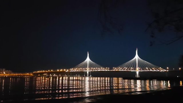 Cable-stayed bridge connects the roads of Western high-speed diameter in St. Petersburg, Russia. Night lighting of bridge is reflected in water of Peter's fairway. Modern industrial road structures