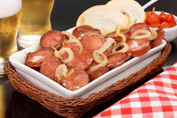 Sliced and fried Calabrese sausage in a pub table in black background