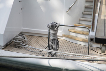 Ropes on board a ship neatly knotted around a metal rail at the foot of a flight of stairs on a...