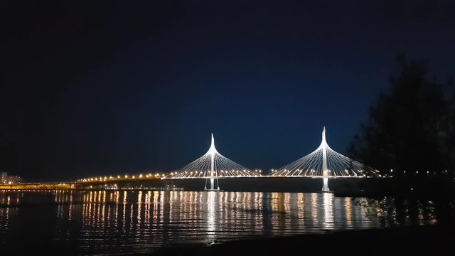 Cable-stayed bridge connects the roads of Western high-speed diameter in St. Petersburg, Russia. Night lighting of bridge is reflected in water of Peter's fairway. Modern industrial road structures