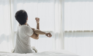 Back of view man wake up and stretching on bed in bedroom in the morning.at home in holiday.