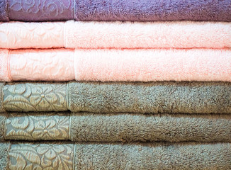 Stack of colorful terry towels folded. Shop Home. Numerous towels stacked and folded on the shelves of a store.