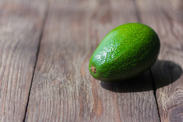 green avocado on wooden background with shallow depth of field