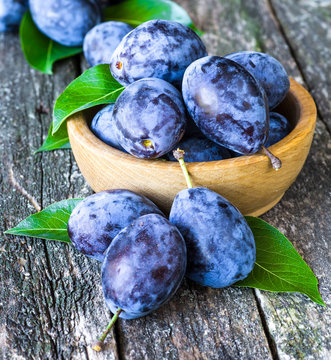 Fresh plums on wooden table background. Half of blue plum fruit. Many beautiful plums with leaves.Harvest. Autumn harvest.