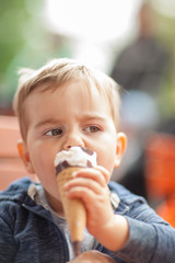Little boy eating an ice outside in the park at a table, summerly mood 