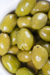 Close-up of olives in a white bowl on white background. Food