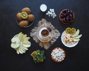 Breakfast with muesli on black background. Black coffee with Turkish sweets, muesli, dates and milk. Sweet food for Ramadan.