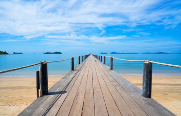 Landscape of wooden bridge in blue sea on tropical beach and blue sky background .