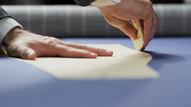 Hands of a Man Drawing a White Line on a Blue Material