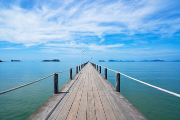 Landscape of wooden bridge in blue sea on tropical beach and blue sky background .