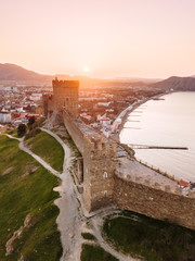 An old defensive fortress with towers in the city of Sudak in the Crimea at dawn from the height.